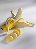 Eine Banane, zum Teil geschält, und Bananenscheiben