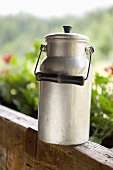 Milk can on a wooden railing