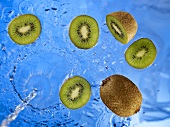 Stream of water running onto kiwi fruit and kiwi fruit slices