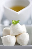 Mozzarella with basil leaf in front of olive oil
