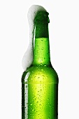 Beer frothing out of green bottle