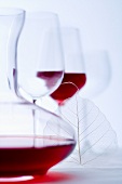 Glass of red wine, carafe and empty wine glasses