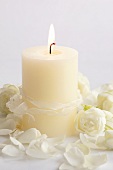 Burning white candle with roses