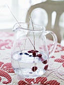 Water with berries in a glass pitcher