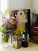 Vases with flowers, red wine bottle and kitchen implements