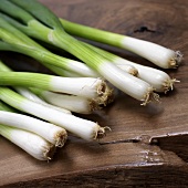 Several spring onions on wooden background