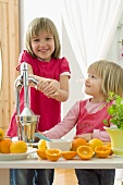 Two girls with fresh citrus fruit and citrus juicer