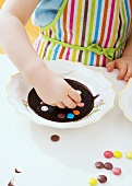 Girl decorating chocolate dessert with coloured chocolate beans
