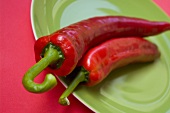 Two red chillies on a green plate