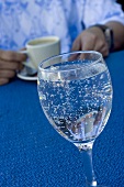 A glass of water, man with a cup of espresso in background