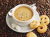 A cup of coffee with sugar cubes and biscuits