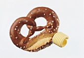 A pretzel with a butter curl against a white background