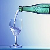 Wasser wird aus Flasche in Glas gegossen