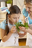 Mother and daughter with fresh herbs in kitchen