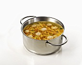 Clear broth with noodles and dumplings in pan