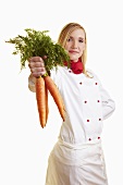 Blond female chef showing bunch of carrots