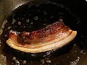 Eine Scheibe Pancetta (Bauchspeck) in Öl anbraten