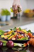 Pouring olive oil over a salad