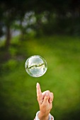 Hand zeigt auf Seifenblase