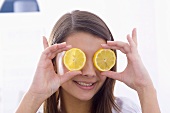 Girl holding lemon slices in front of her eyes