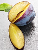 Fresh plum, a section cut out, with drops of water