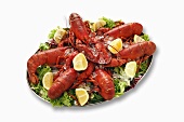 Cooked lobsters on salad leaves with lemon wedges