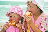 Children eating pizza by the sea