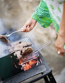 Woman barbecuing meat out of doors