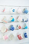 Various mugs and cups hanging on a wooden wall