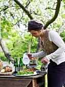 Frau zuckert Erdbeertorte am Buffet im Garten (Schweden)