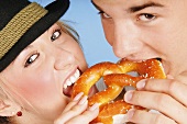 Young couple eating the same pretzel