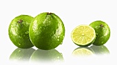 Limes, whole and halved, with drops of water and reflections