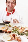 Chef with grilled prawns and glass of red wine