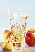 Ice cube falling into glass of apple juice