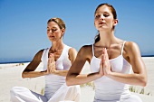 Two women doing yoga exercises on beach