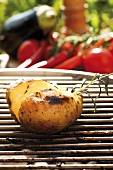 Barbecued potato on barbecue, vegetables in background