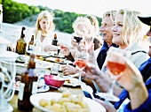 Frauen und Männer feiern beim Essen am See