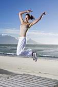 South Africa, Cape Town, Young woman jumping on beach