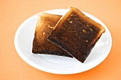 Two slices of burned toast on plate, close-up, elevated view