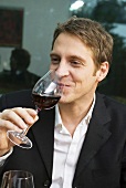 Junger Mann trinkt ein Glas Rotwein