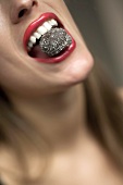 Frau mit einer Schokoladenpraline im Mund