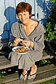 Woman in bathrobe holding plate of prawns