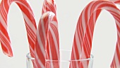 Red and white striped candy canes in a glass