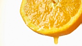 Orangensaft tropft von Orangenhälfte