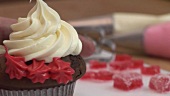 Schokoladen-Cupcake mit roter Zuckercreme verzieren