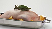 Stuffed duck (oven-ready) with oranges in a roasting dish