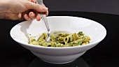 Penne with pesto being eaten