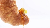 Honig fliesst auf Croissant mit Butterstück