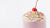 Milkshake with cream, sprinkles and cocktail cherry (detail)