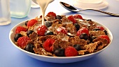 Pouring milk over cornflakes with berries